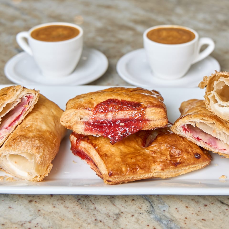 Cuban pastelitos with guava and cheese filling served with two cups of cafe con leche.
